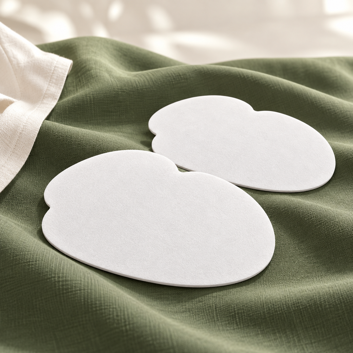 AI-productillustratie: detail van twee witte okselpads op mosgroene stof; de werkelijke kleur en het materiaal zijn nog niet bevestigd.